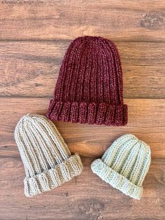 two knitted hats sitting on top of a wooden floor