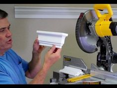 a man holding a piece of paper in front of a machine that is working on it