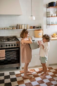 two children standing in the kitchen playing with each other