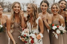 a group of women standing next to each other with bouquets in their hands and smiling at the camera