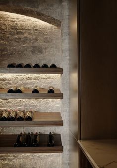 several shelves with wine bottles on them in a room that has stone walls and flooring