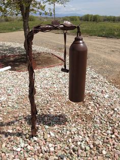 a fire extinguisher next to a tree with rocks and gravel around it