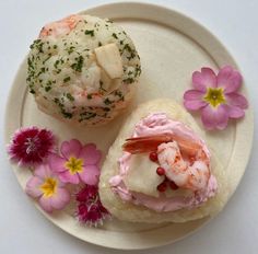 there is a sandwich with shrimp on it next to some pink flowers and daisies