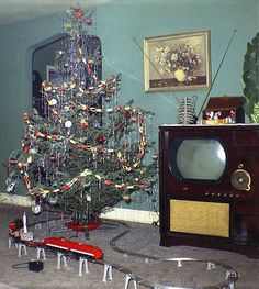 a small christmas tree sitting in front of a tv on top of a carpeted floor