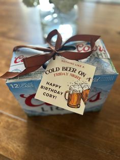 a beer can wrapped in brown ribbon on top of a wooden table