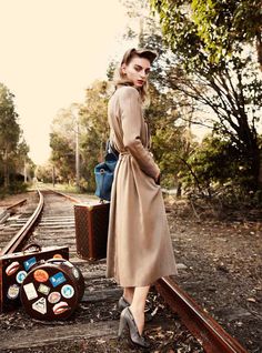 a woman standing on train tracks next to suitcases