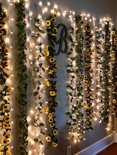 sunflowers and greenery are hung on the wall with lights around them for decoration