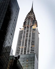 the top of a tall building with lights on it's sides in front of other buildings