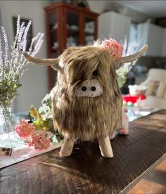 a stuffed animal sitting on top of a wooden table next to vases and flowers