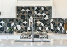 a kitchen with white cabinets and black tiles on the backsplash is seen in this image