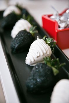 some black and white strawberries are sitting on a tray