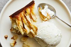 a piece of cake and ice cream on a white plate with a spoon next to it