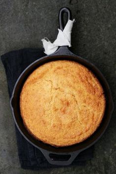 a baked cake in a cast iron skillet on top of a black cloth with a white napkin