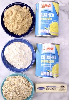 three bowls with oatmeal and other ingredients on a marble counter top next to a can of butter