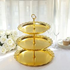 three tiered trays on a table with white flowers and wine glasses in the background