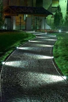 a walkway lit up with lights in front of a house