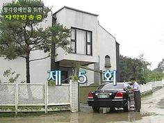 a man standing next to a car in front of a building with korean writing on it