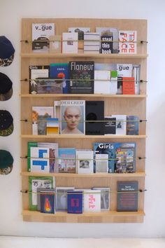 there is a book shelf with many books on it and two hats hanging from the wall