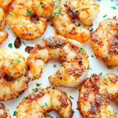 grilled shrimp on a white plate with parsley sprinkled around the edges