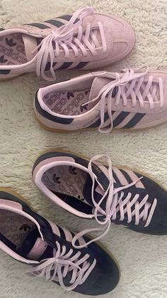 three pairs of pink and blue tennis shoes sitting on top of a white carpeted floor