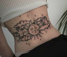 a woman's stomach with an image of the sun and clouds on it,