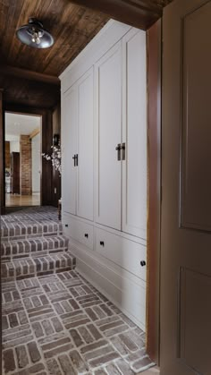 a hallway with white cabinets and carpeted stairs