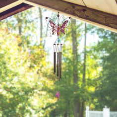 a wind chime hanging from the side of a wooden roof with trees in the background