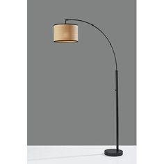 a black floor lamp with a beige shade on the top and an oval light fixture