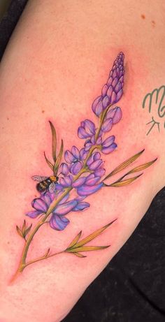 a tattoo with purple flowers and a bee on it