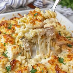 a fork is lifting up some pasta from the casserole dish with chicken and parmesan cheese