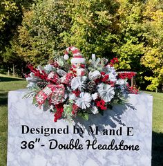 a christmas wreath on top of a sign in the grass with trees and bushes behind it