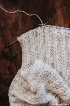 a close up of a knitted object on a wooden surface with scissors and thread