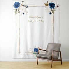 a chair sitting in front of a white wall with blue flowers on it and a gold frame