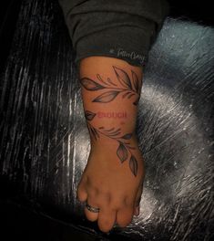 a person's foot with a tattoo on it that says enough and leaves in the background