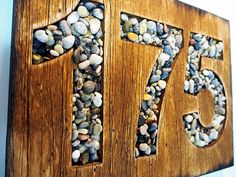 a wooden sign with rocks in the shape of number seventy five on it's side