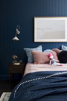 a bedroom with blue walls and pink bedding, an art work on the wall