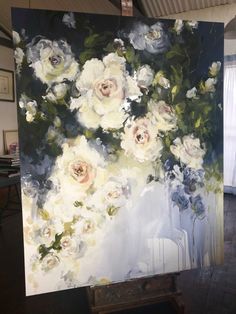 an easel is holding up a painting with white and blue flowers