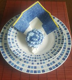 a white plate topped with a blue flower on top of a wooden table next to a napkin