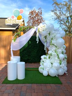 a balloon arch with white balloons and greenery