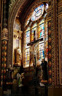 an ornate church with stained glass windows and statues in front of the alter, including a crucifix