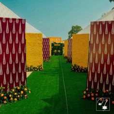 an outdoor area with grass, flowers and red drapes on the walls that have raindrops hanging from them