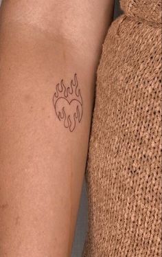 a woman's arm with a tattoo on it that has flames coming out of it