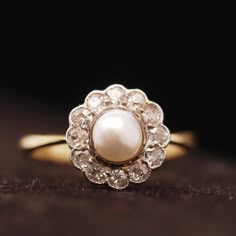 an antique pearl and diamond ring on a brown surface, with the background showing dark wood