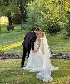 a bride and groom kissing in the grass