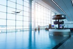 an airplane is flying in the sky over a building with large windows and blue flooring