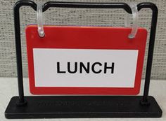 an orange and white sign that says meeting in black lettering on it, sitting on a stand