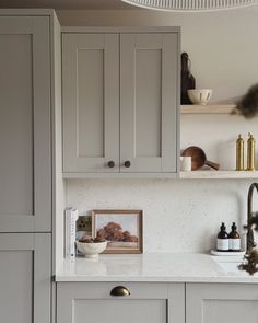 a kitchen with gray cabinets and white counter tops is seen in this image from the front view