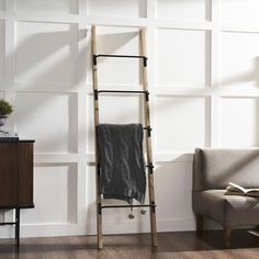 a ladder leaning against the wall with a towel hanging on it's side, next to a chair