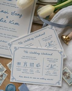 the wedding stationery is laid out on top of some fabric and ribbon, with tulips in the background