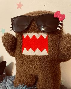 a stuffed animal with sunglasses on it's face and mouth is posed in front of a wall